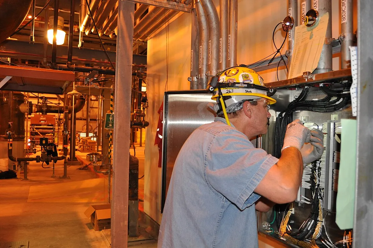 Electrician working at a control cabinet wearing a hard hat